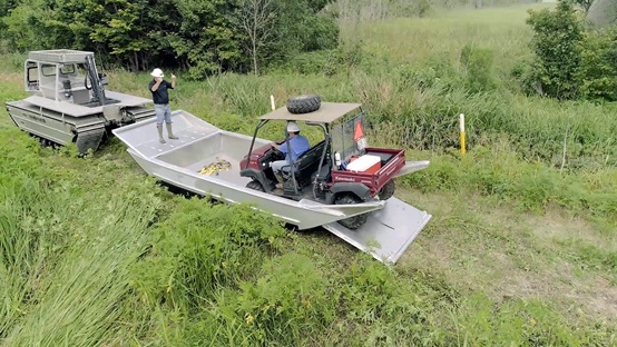 A golf cart being loaded onto a Slick Sled™️ amphibious transport system attached to a Marsh Master® marsh buggy